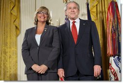 President George W. Bush joins military spouse Cindy Bjerke of Spanaway, Wash., on stage in the East Room of the White House, to receive the President’s Volunteer Service Award Friday, May 11, 2007, during a commemoration of Military Spouse Day. White House photo by Eric Draper