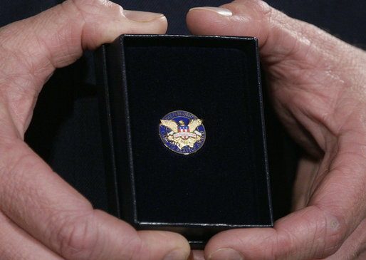 A White House military aide holds the President's Volunteer Service Award medal presented by President George W. Bush to military spouses Friday, May 11, 2007 at the White House, in honor of their outstanding volunteer service and to commemorate Military Spouse Day. White House photo by Eric Draper