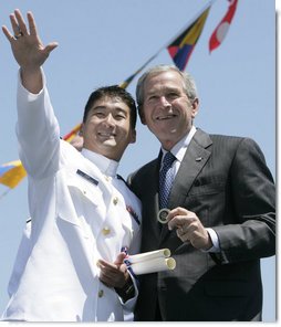 President George W. Bush holds a coin presented to him by U.S. Coast Guard graduate Daniel Kyung-Hyun Han, after President Bush presented him with his commission Wednesday, May 23, 2007, at the U.S. Coast Guard Academy commencement in New London, Conn. White House photo by Joyce N. Boghosian