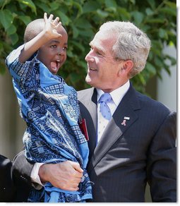 President George W. Bush holds Baron Mosima Loyiso Tantoh in the Rose Garden of the White House Wednesday, May 30, 2007, after delivering a statement on PEPFAR, the President's Emergency Plan for AIDS Relief. Baron's mother, Kunene Tantoh, representing Mothers to Mothers, an organization which provides treatment and support services for HIV-positive mothers in South Africa, joined President Bush with other guests in the Rose Garden for the statement. White House photo by Eric Draper