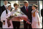 Mrs. Laura Bush holds flowers presented to her by Sara Shehu, 12, and Frensis Spaho, 13, upon the arrival Sunday, June 10, 2007, of she and President George W. Bush to Albania. The visit marked the first by a sitting U.S. president to the country. White House photo by Chris Greenberg