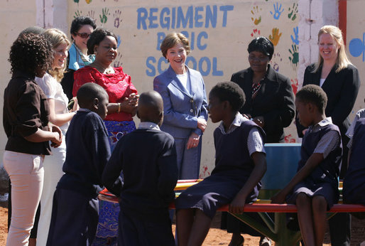 Mrs. Laura Bush and Ms. Jenna Bush stand with Zambian First Lady Mrs. Maureen Mwanawasa, dressed in red, and her daughter Ms. Chipo Mwanawasa, far left, as they watch children demonstrate how the PlayPump works at the Regiment Basic School Thursday, June 28, 2007, in Lusaka, Zambia. Working similar to a merry-go-round, the PlayPump pumps clean drinking water into a reservoir tank as the children sit on and spin it. Before the pump was installed many of the 1,200 students at the school had to bring water to school or walk long distances to find water. The school also has used the water to expand its garden, providing fresh vegetables to the more vulnerable students. White House photo by Lynden Steele