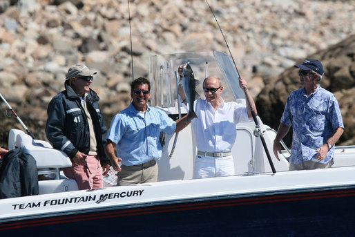 With former President George H.W. Bush and President George W. Bush looking on, Russia's President Vladimir Putin holds up his catch Monday, July 2, 2007, with the help of fishing guide Billy Bush, during a morning outing at Walker's Point in Kennebunkport, Me. White House photo by Eric Draper