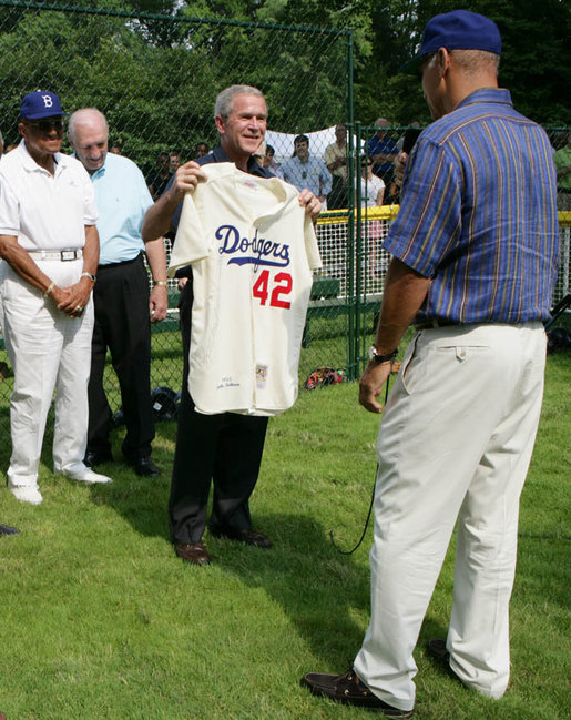 President George W. Bush holds up a commemorative baseball jersey with Jackie Robinson's number 42 presented to him by players from Robinson's playing era at the White House Tee Ball Game Sunday, July 15, 2007. Tee Ball players wore the number 42 to celebrate the legacy of Jackie Robinson. More about Tee Ball on the South Lawn. White House photo by Chris Greenberg