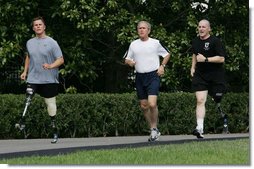 President George W. Bush jogs along the White House jogging track with wounded veterans U.S. Army Sgt.Neil Duncan (Ret.), left, and U.S. Army Specialist Max Ramsey Wednesday, July 25, 2007. White House photo by Chris Greenberg