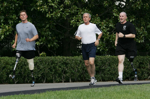 President George W. Bush jogs along the White House jogging track with wounded veterans U.S. Army Sgt. Neil Duncan (Ret.), left, and U.S. Army Specialist Max Ramsey Wednesday, July 25, 2007. White House photo by Chris Greenberg