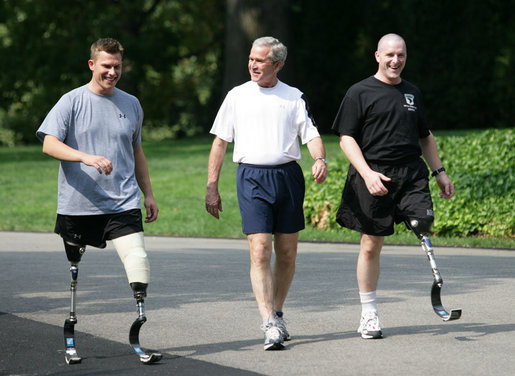 President George W. Bush meets with wounded veterans U.S. Army Sgt. Neil Duncan (Ret.), left, and U.S. Army Specialist Max Ramsey, right, for a jog Wednesday, July 25, 2007 around the South Lawn of the White House. White House photo by Eric Draper