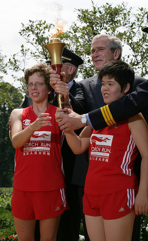 President George W. Bush and Police Chief Russ Laine of Algonquin, Ill., stand with torch runners Karen Dickerson of Springfield, Va., left, and Qiao Meili of Shanghai, China, during a Special Olympics Global Law Enforcement Torch Run Ceremony Thursday, July 26, 2007, in the Rose Garden. White House photo by Eric Draper