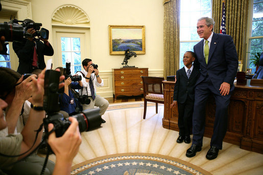 President George W. Bush and Ezekiel “Zeek” Taylor, 8, of Durham, N.C., the 2007 March of Dimes National Ambassador, pose for photographers during their meeting in the Oval Office at the White House Monday, July 30, 2007. White House photo by Eric Draper