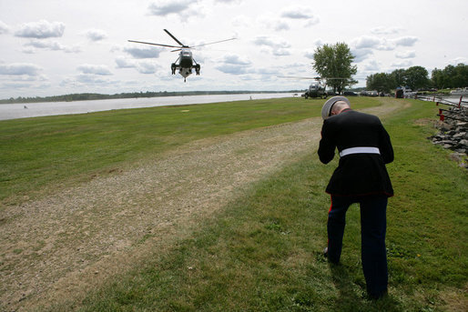 A U.S. Marine holds on to his cap and braces himself against the rotor wash of Marine One as President George W. Bush arrives Monday, Aug. 20, 2007 at the landing zone in Montebello, Canada, to attend the North American leaders' summit. White House photo by Eric Draper