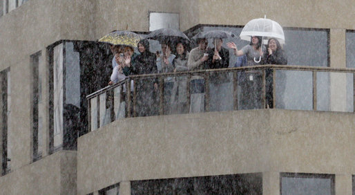 Spectators shelter themselves from a bitter rain Thursday, Sept. 6, 2007, as they wave to a motorcade carrying President George W. Bush through the streets of Sydney. White House photo by Eric Draper