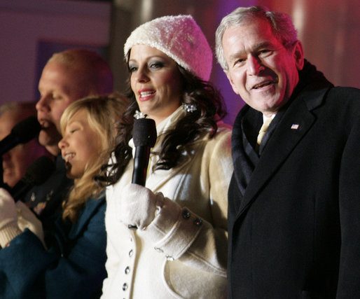 President George W. Bush joins Sara Evans in singing "We Wish you a Merry Christmas" on stage at the Ellipse Thursday, Dec. 6, 2007, during the festivities surround the lighting of the National Christmas Tree. White House photo by Shealah Craighead