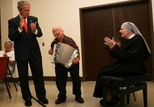 President George W. Bush and Sister Therese Noel join the festivities as they listen to 75-year-old resident Joe Dignazio of West Virginia, play "The Eyes of Texas" during a visit Tuesday, Dec. 18, 2007, to the Washington, D.C. facility. The President told Mr. Dignazio, "You are really good! Keep playing!" White House photo by Shealah Craighead