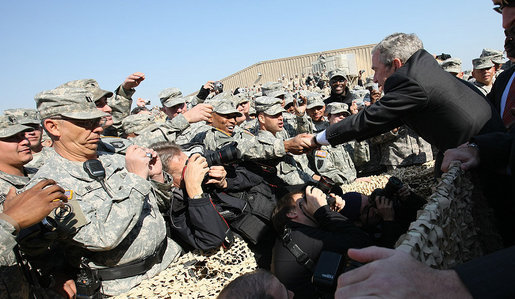 Troops reach out for President George W. Bush as he leaves the stage after delivering remarks to military personnel and coalition forces at Camp Arifjan before departing Kuwait Saturday, Jan. 12, 2008, for Bahrain. White House photo by Eric Draper