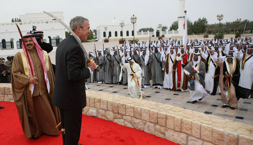 President George W. Bush enjoys the moment with performers Saturday, Jan. 12, 2008, after being presented with a sword by King Hamad Bin Isa Al-Khalifa, left, during arrival ceremonies in Manama, Bahrain. White House photo by Eric Draper