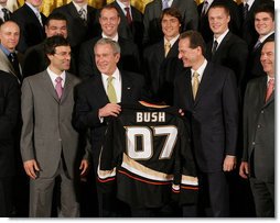 President George W. Bush stands between Scotty Niedermayer, left, and Ducks' owner Henry Samueli as he holds up a BUSH 07 Anaheim Ducks jersey Wednesday, Feb. 6, 2008, after welcoming the 2007 Stanley Cup champions to the East Room of the White House. White House photo by Eric Draper