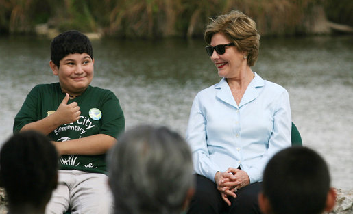 Mrs. Laura Bush smiles as a Florida City Elementary School student gives a thumbs-up while sitting on stage with Mrs. Bush, Wednesday, Feb. 6, 2008, during the Junior Ranger "First Bloom" planting event in Everglades National Park, Fla. Mrs. Bush praised the Everglades restoration program which will help bring back native trees in areas of the Everglades overgrown with non-native plants. White House photo by Shealah Craighead