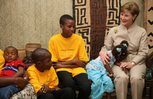A young girl rests her head on Mrs. Laura Bush’s lap Sunday, Feb. 17, 2008, as she visits with orphans and caretakers in the Living Room of the WAMA Foundation, a non-profit organization founded by Salma Kikwete, First Lady of Tanzania. White House photo by Shealah Craighead