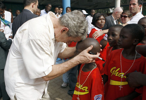 President George W. Bush embraces a young boy after a tee ball game Wednesday, Feb. 20, 2008, at the Ghana International School in Accra, Ghana. White House photo by Eric Draper