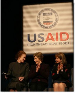 Mrs. Laura Bush applauds as she's joined on stage by Ms. Henrietta Fore, left, Administrator of the U.S. Agency for International Development and Director of the United States Foreign Assistance, and Ambassador Paul Dobriansky, Under Secretary of State for Democracy and Global Affairs, for the USAID Celebration of International Women's Day Friday, March 7, 2008, at the Ronald Reagan Building in Washington, D.C. White House photo by Joyce N. Boghosian
