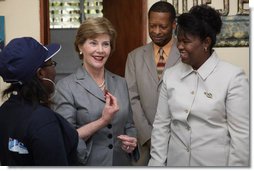 Mrs. Laura Bush, joined by Guerda Previlon, right, chief of party IDEJEN, and Gabriel Bienime, Haiti Education Minister, visits with a student enrolled in the IDEJEN educational program at the College de St. Martin Tours Thursday, March 13, 2008, in Port-au-Prince, Haiti. In an address to the faculty and staff Mrs. Bush said, “Educating its young people is one of the best things a country can do to ensure its continued development.”  White House photo by Shealah Craighead