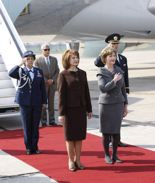 Mrs. Laura Bush holds her hand over her heart during the playing of the national anthem Wednesday, April 2, 2008, as she stands with Mrs. Maria Basescu, spouse of Romania's President Traian Basescu, on the red carpet during the arrival ceremony at Mihail Kogalniceanu Airport in Constanta, Romania. White House photo by Eric Draper