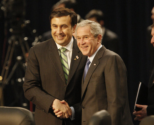 President George W. Bush and President Mikheil Saakashvili of Georgia, shake hands as they smile at cameras before the start of the afternoon session of the 2008 NATO Summit in Bucharest. White House photo by Eric Draper