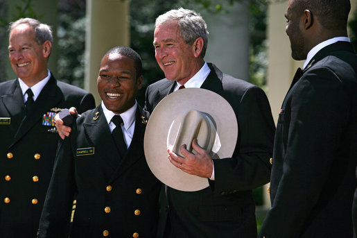 President George W. Bush is presented a cowboy hat and a Commander-in-Chief Trophy ring by Co-Captains Reggie Campbell, left, and Irv Spencer Monday, April 14, 2008, during the presentation of the Commander-in-Chief's Trophy to the United States Naval Academy Football Team in the Rose Garden at the White House. White House photo by Noah Rabinowitz