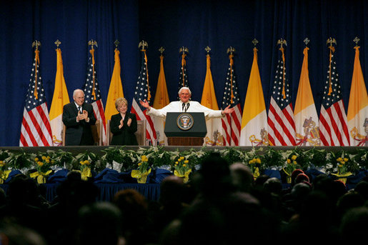 Pope Benedict XVI, joined on stage by Vice President Dick Cheney and Mrs. Lynne Cheney, gestures to the faithful Sunday, April 20, 2008 at a farewell ceremony for the Pope at John F. Kennedy International Airport in New York. White House photo by Shealah Craighead