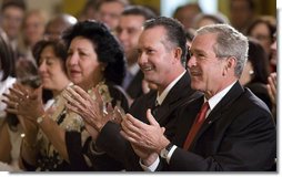 President George W. Bush applauds the entertainment of vocalist Willy Chirino during a Day of Solidarity with the Cuban People Wednesday, May 21, 2008, in the East Room of the White House. Seated next to him are Miguel Sigler Amaya, a former political prisoner, and his wife, Josefa Lopez Pena.  White House photo by Joyce N. Boghosian