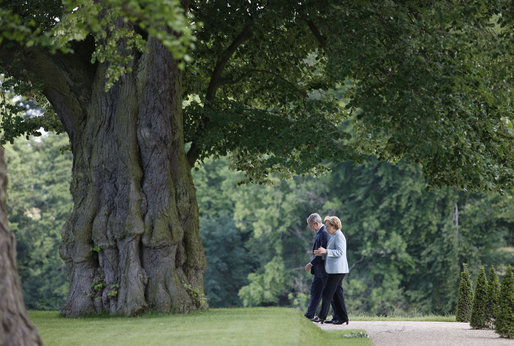 President George W. Bush walks with Germany's Chancellor Angela Merkel on the grounds of the Schloss Meseberg Wednesday, June 11, 2008, during the President's visit to Europe. The two spent the day in meetings and held a joint press availability before the President continued on to Rome. White House photo by Eric Draper