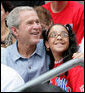 President George W. Bush poses for a photo with a fan in the stands Monday, June 30, 2008, during the opening game of the 2008 Tee Ball season between the Cramer Hill Little League Red Sox of Camden, N.J., and the Jose M. Rodriguez Little League Angels of Manati, Puerto Rico, on the South Lawn of the White House. White House photo by Chris Greenberg