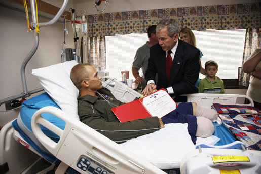 President George W. Bush awards a Purple Heart and citation to U.S. Marine Corps Sgt. Justin Clenard of Tehachapi, Calif., Thursday, July 3, 2008, at the National Naval Medical Center in Bethesda, Md. Looking on is Sgt. Clenard's father, Christopher Clenard, his stepmother, Kerrin Clenard, and his brother, Kevin Clenard. At far right is his mother, Lori Sander. White House photo by Eric Draper