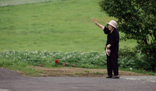 A resident of Makkari waves as the G-8 Spouses pass by en route Tuesday, July 8, 2008, to Hokkaido Marche, a farmer’s market, on Japan's northern island of Hokkaido, site of the 2008 G-8 Summit. White House photo by Shealah Craighead