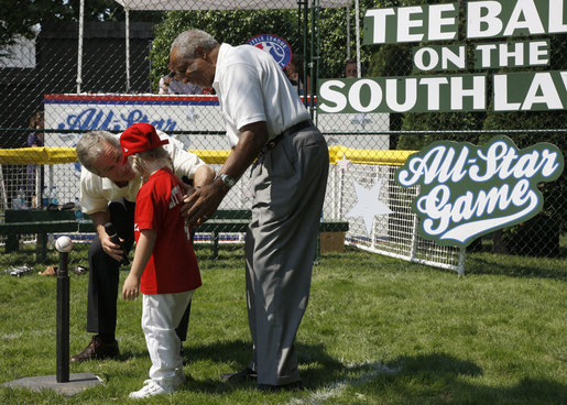 President George W. Bush and Hall of Famer Frank Robinson offer words of encouragement to 8-year-old Shelby Shayler of the Little League Challenger Division in Norfolk, Va., Wednesday, July 16, 2008, as she places a ball on the tee to start the first game of a doubleheader on the South Lawn of the White House. White House photo by Eric Draper