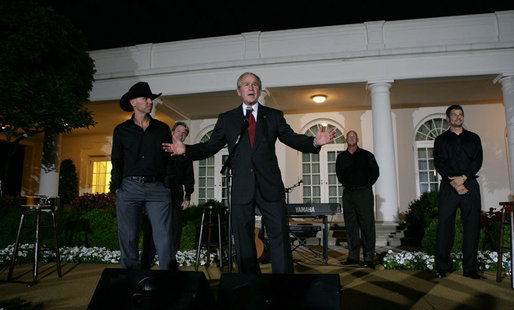 With Kenny Chesney listening in, President George W. Bush addresses guests in the Rose Garden Wednesday, July 16, 2008, following the Social Dinner in Honor of Major League Baseball. The President told his audience, "“It doesn’t get much better than this – country music in the Rose Garden and celebrating baseball.” White House photo by Chris Greenberg