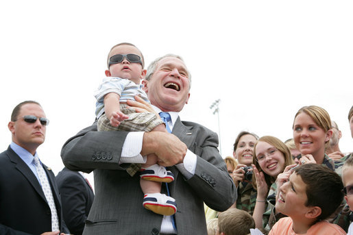 President George Bush shares a laugh as he holds baby while greeting military personnel and families upon departure from the Greater Peoria Regional Airport - Air National Guard Ramp in Peoria, IL Friday, July 25, 2008. White House photo by Chris Greenberg