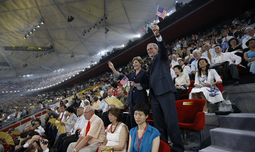 President George W. Bush waves an American flag as he and Mrs. Laura Bush stand and cheer during the entrance of the U.S. athletes into China's National Stadium Friday, Aug. 8, 2008, in Beijing. White House photo by Eric Draper
