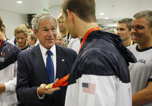 President George W. Bush holds the Olympic gold medal of U.S. Olympic swimmer Michael Phelps, after congratulating Phelps on his first Olympic gold performance Sunday, Aug. 10, 2008, at the National Aquatics Center in Beijing. White House photo by Eric Draper