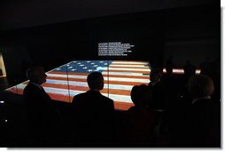 President George W. Bush is silhouetted against an American flag exhibit Wednesday, Nov. 19, 2008, during his visit with Mrs. Laura Bush to the National Museum of American History in Washington, D.C. White House photo by Eric Draper