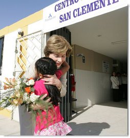 Mrs. Laura Bush hugs a young girl after she was presented with a bouquet of flowers upon her arrival welcome to the San Clemente Health Center Friday, Nov. 21, 2008, in San Clemente, Peru. Mrs. Bush visited the center and participated in interactive demonstrations depicting community-based health training. White House photo by Joyce N. Boghosian