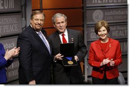 President George W. Bush, joined by Mrs. Laura Bush, is presented with the International Medal of PEACE by Pastor Rick Warren, Monday, Dec. 1, 2008, following their participation at the Saddleback Civil Forum on Global Health in Washington, D.C. White House photo by Eric Draper