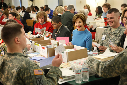 Mrs. Laura Bush is seated between volunteers Master Tre'shaad Cox, 11, left, and U.S. Army Sgt. Thomas Griffin, an out-patient at Walter Reed Army Medical Center, during a visit Saturday, Dec. 6, 2008, to the American Red Cross Holiday Mail for Heroes Packing Event at the Red Cross National Headquarters in Washington, D.C. Mrs. Bush reminded the volunteers that during this holiday season, "we are reminded of our many blessings, especially our freedom. The American Red Cross Holiday Mail for Heroes project, in partnership with Pitney Bowes, provides citizens an opportunity to send holiday cards to members of our Armed Forces. I am grateful to the many volunteers gathered here today to ensure our military receives our message of thanks for the sacrifice they make each day to defend our freedom." White House photo by Chris Greenberg