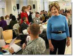 Mrs. Laura Bush greets one of the military volunteers and his child during the Saturday, Dec. 6, 2008, American Red Cross Holiday Mail for Heroes event in Washington, D.C. Standing in the background are American Red Cross President and CEO Gail McGovern, in red, and Bonnie McElveen-Hunter, Chairman of the American Red Cross. As the room full of volunteers sorted cards created by Americans to send to U.S. troops deployed around the world, Mrs. Bush encouraged Americans to do volunteer work in their home towns for those in need of food, care or appreciation. Cards for the troops can still be sent until December 10th at designated post office boxes.  White House photo by Chris Greenberg