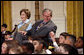 President George W. Bush, sitting with Mrs. Laura Bush, reaches to hold the hand of a young child Monday, Dec. 8, 2008 in the East Room of the White House, during the Children's Hoilday Reception and Performance. White House photo by Eric Draper