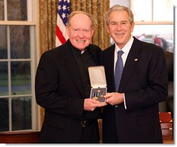 President George W. Bush stands with Father Tim Scully, CSC, after presenting him with the 2008 Presidential Citizens Medal Wednesday, Dec. 10, 2008, in the Oval Office of the White House.  White House photo by Chris Greenberg