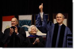 With former President George H.W. Bush and Mrs. Barbara Bush looking on, President George W. Bush gives the thumbs-up to the audience as he stands onstage Friday, Dec. 12, 2008, in Reed Arena where he delivered the commencement address at Texas A& M University in College Station, Texas. White House photo by Eric Draper