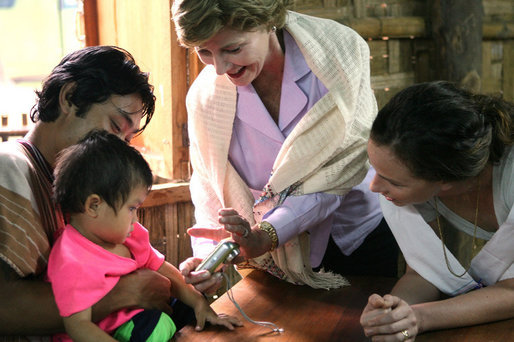 Mrs. Laura Bush and daughter Barbara Bush, show a camera to a young family at the Mae La Refugee Camp August 7, 2008, in Mae Sot, Thailand. White House photo by Shealah Craighead
