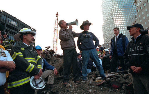 With retired firefighter Bob Beckwith standing next to him, President George W. Bush uses a bullhorn to address rescue workers Sept. 14, 2001, at Ground Zero, the site of the terrorist attack on the World Trade Center. White House photo by Eric Draper