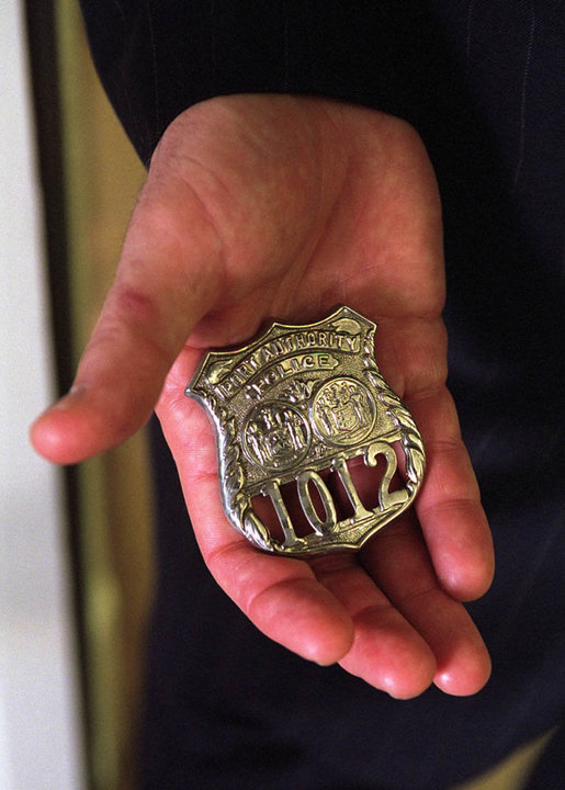 President George W. Bush holds a Port Authority Police Shield #1012 in his hand in the Oval Office, Oct. 15, 2001, at the White House. The badge was worn by George Howard when he was killed responding to the terrorist attack on the World Trade Center, and was presented to the President by Officer Howard's mother, Arlene Howard. White House photo by Eric Draper